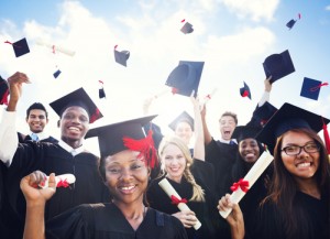 College grads at ceremony happy, tossing caps and smiling for the camera