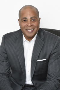 Image of a sales leader sitting with a gray suit, white shirt and no necktie