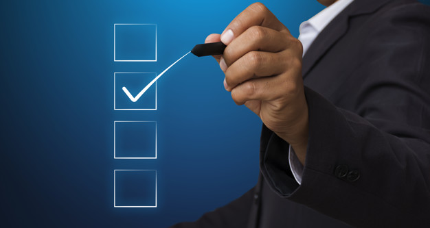 Man in a suit uses a marker to make a check mark on a glass with three square boxes on it