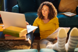 Focused woman working on laptop while sitting on the floor, embodying Social Media Job Success strategies.