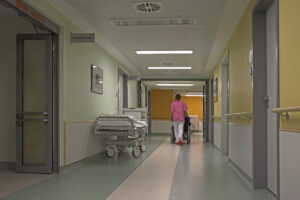 Empty hospital corridor with healthcare worker walking down the hall.