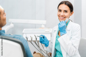 Female dental assistant sitting with a patient in the chair