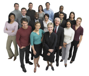 A diverse group of professionals standing together, smiling, and posing for a group photo. The group includes men and women of various ages and ethnicities, dressed in business and casual attire