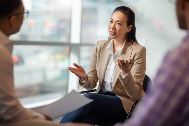 Business professional practicing active listening in sales, engaging in a focused conversation with colleagues, demonstrating attentive communication skills.